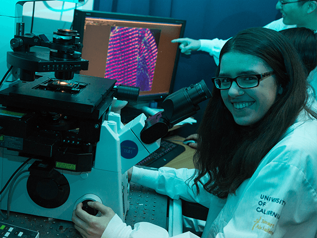 An MCIP graduate student works at a microscope